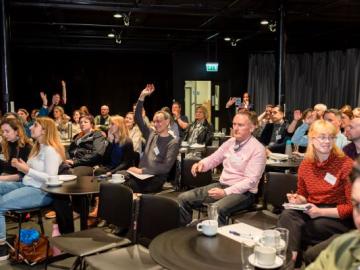 Image of people siting round tables at Creu Cymru Conference