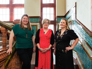 Three women stood facing the camera on a staircase